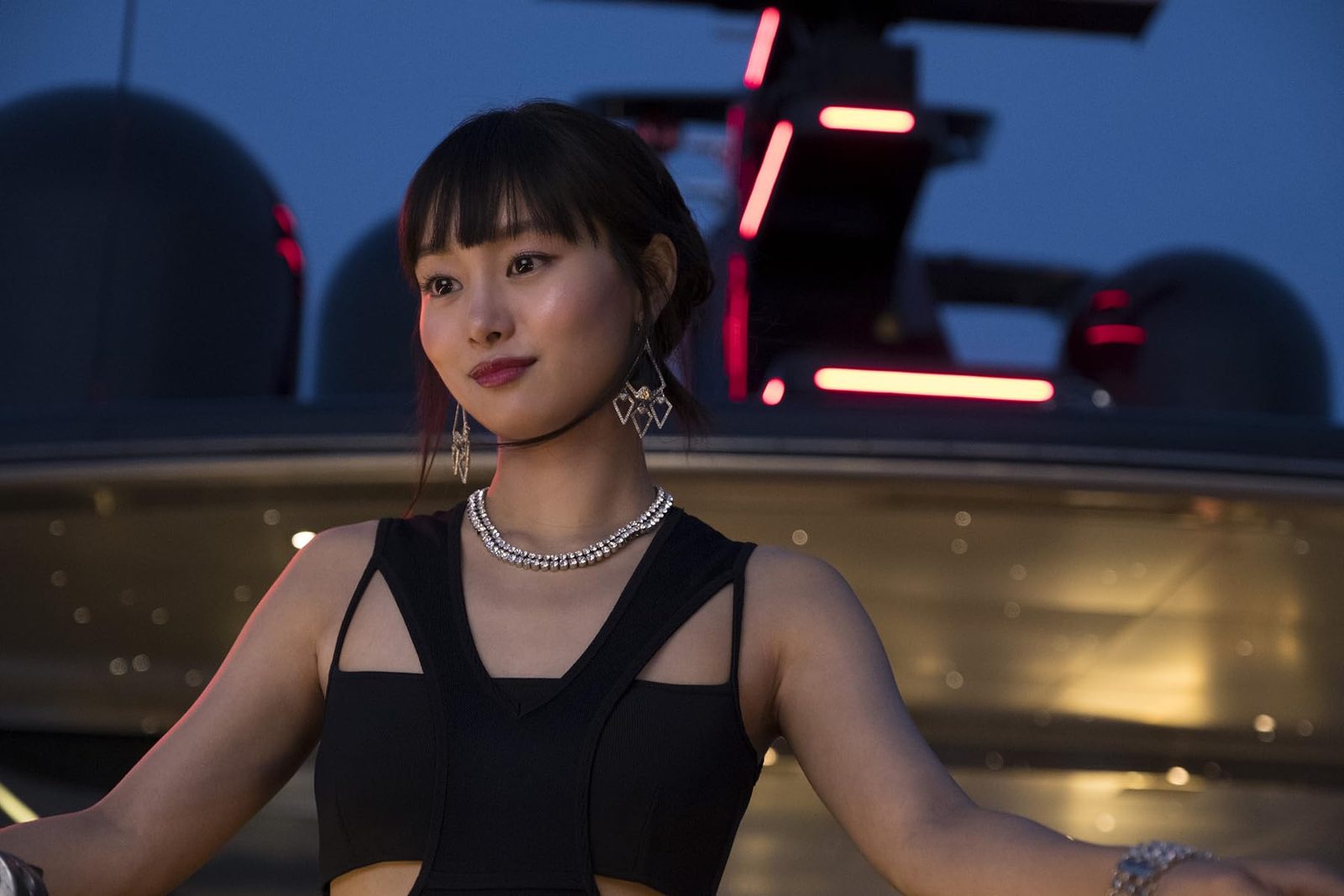 一名穿黑色礼服的女子站在夜间灯光前