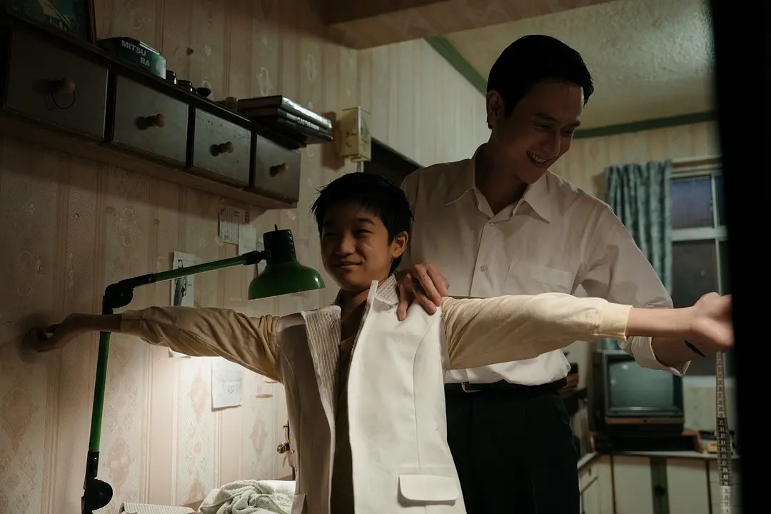 父亲在狭小的出租屋里为廖界比试自己缝制的衣服